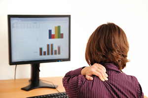 Cervical osteochondrosis in a woman sitting next to a computer